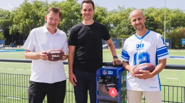 Drei Männer stehen vor einem Schrank mit Ausrüstung zum Flag Football spielen