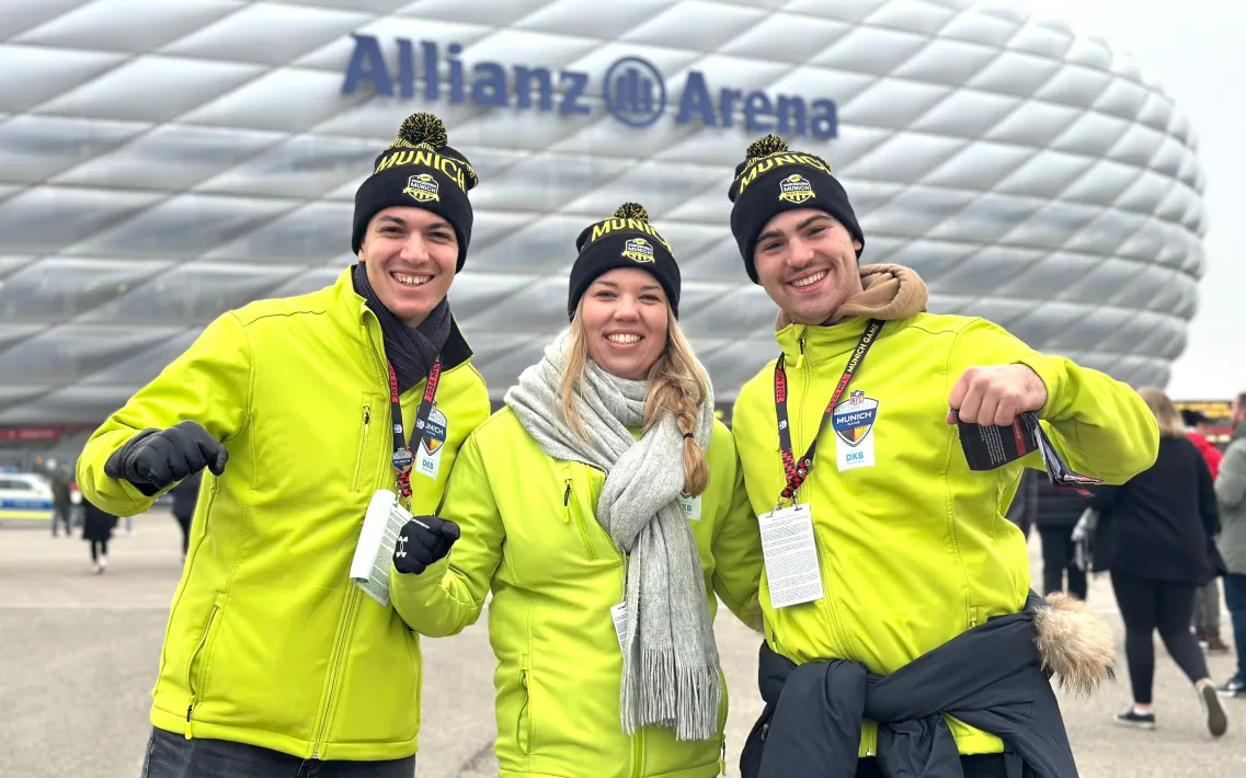 Drei Volunteers des NFL Munich Game 2024 vor der Allianz Arena