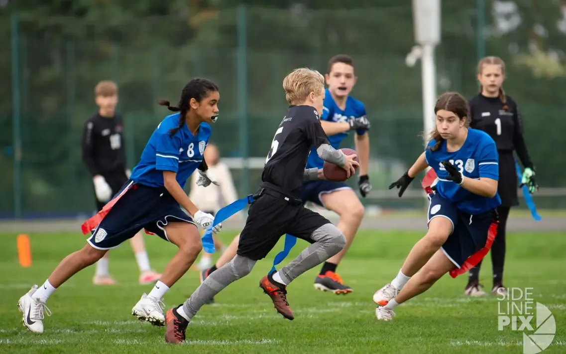 Mehrere Jugendliche spielen Flag Football auf einem Rasenplatz